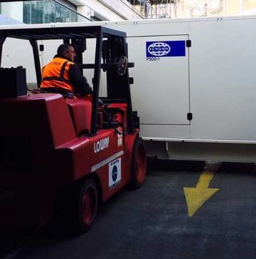 A forklift and forklift operator moving a large power generator